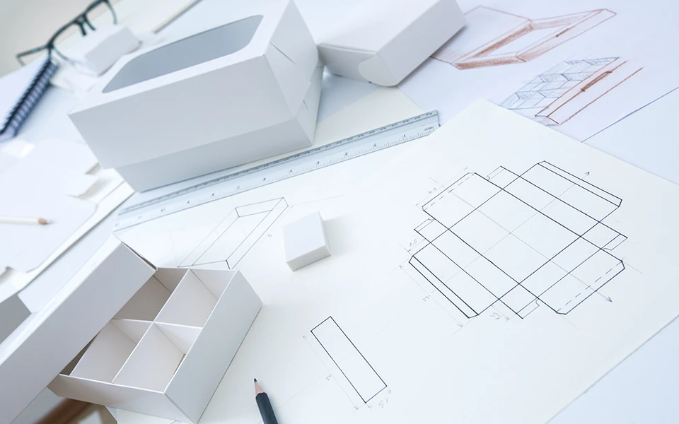 Design process for innovative packaging with Ingersoll Paper Box, featuring carton engineering sketches and prototype boxes.