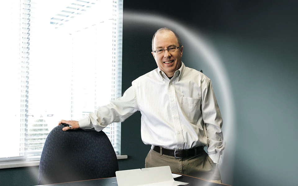 Photograph of David Skinner, third-generation leader, smiling next to his office chair, symbolizing the continued growth and evolution of Ingersoll Paper Box through family-led management and technological advancements.