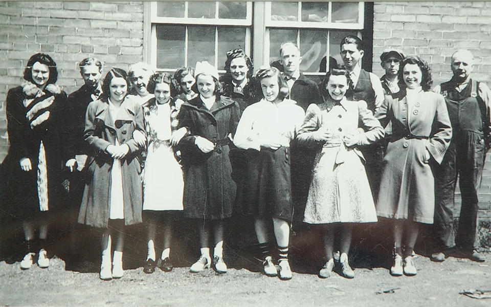 Historic group photo of Ronald Skinner with his team outside the Ingersoll Paper Box facility, highlighting the collaborative spirit and family-like workforce during the company's early growth in the Canadian market.