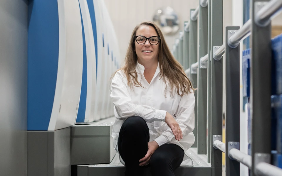 Photograph of Sarah Skinner, third-generation leader, smiling next to his office chair, symbolizing the continued growth and evolution of Ingersoll Paper Box through family-led management and technological advancements.